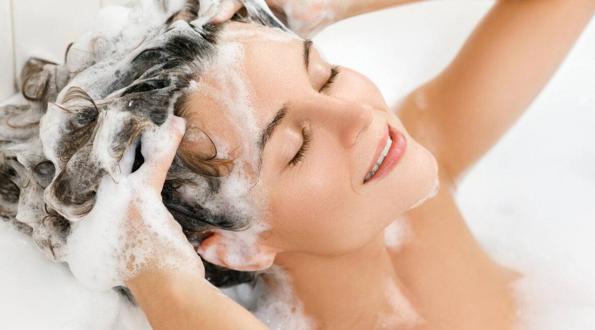 junge Frau wäscht ihre Haare mit shampoo