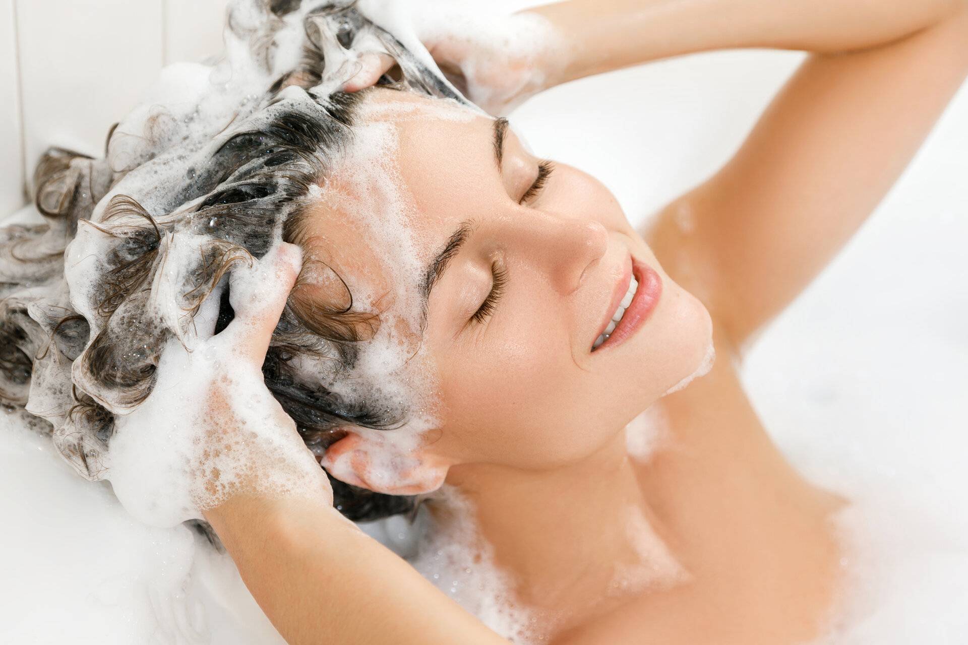 junge Frau wäscht ihre Haare mit shampoo