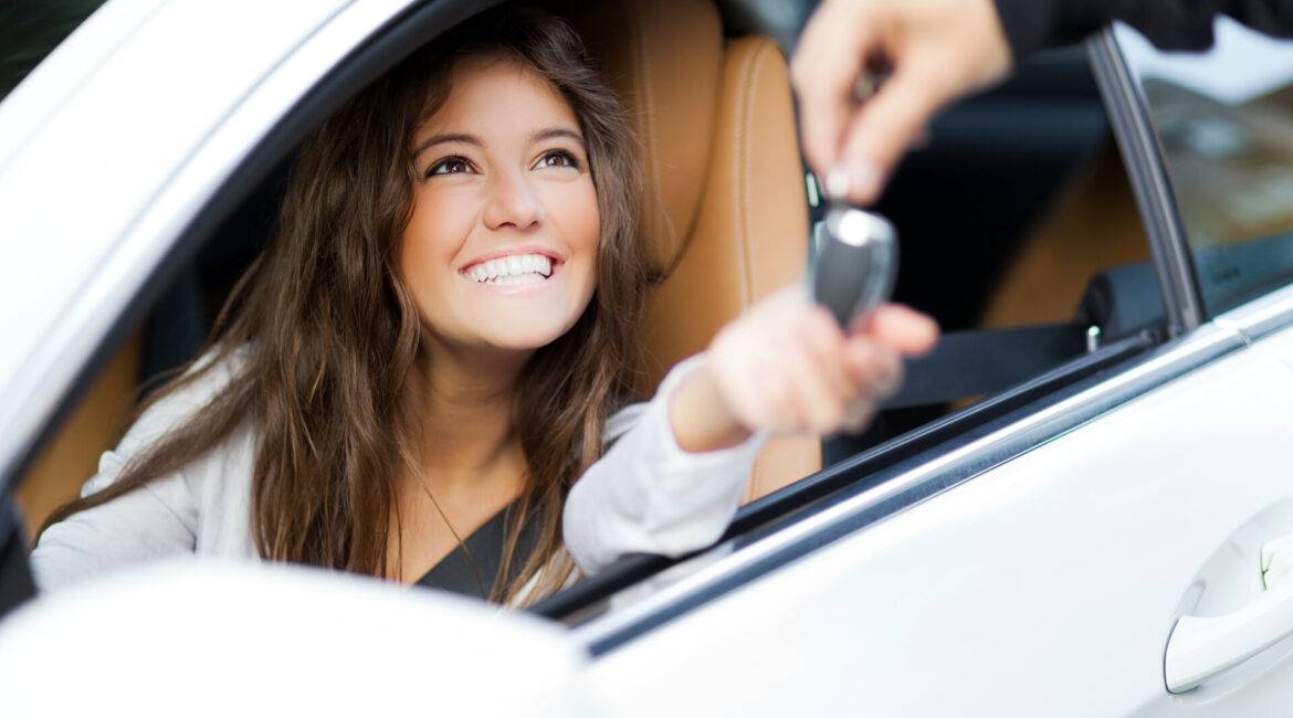 Frau erhält die Schlüssel für ihr neues Auto vom Händler