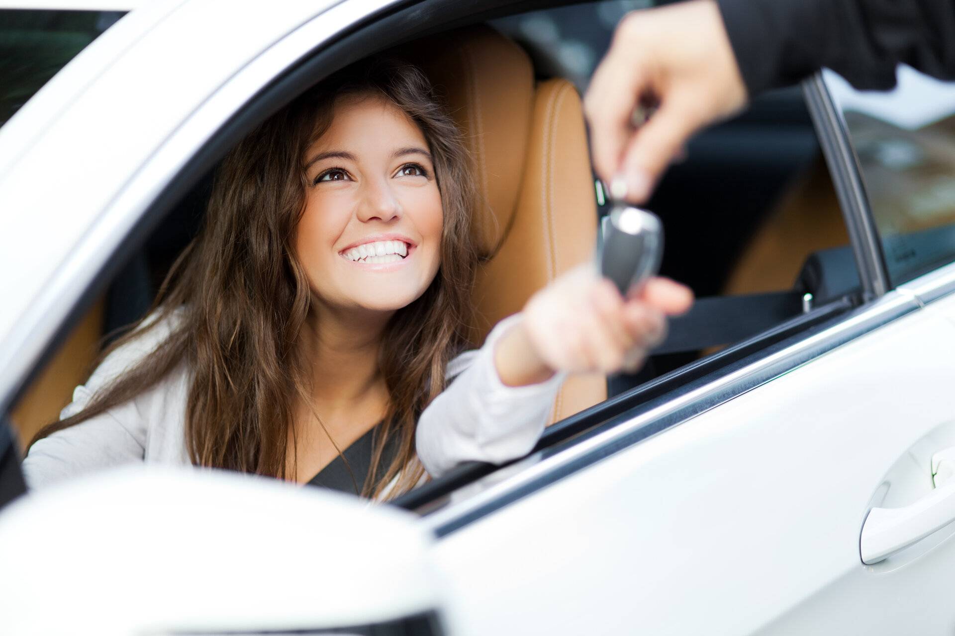 Frau erhält die Schlüssel für ihr neues Auto vom Händler