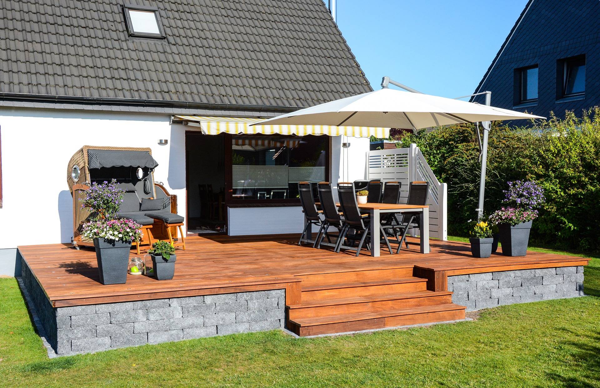 Holzterrasse mit Sitzgruppe, Sonnenschirm und Gartenblick | Sonnenschutz Markisen
